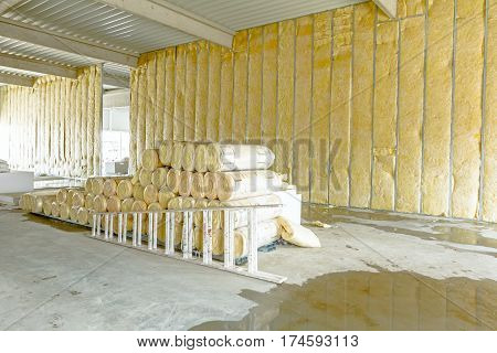 Stack of thermal insulation material in roll is wrapped with cellophane foil. Used wooden ladder to complete dividing wall
