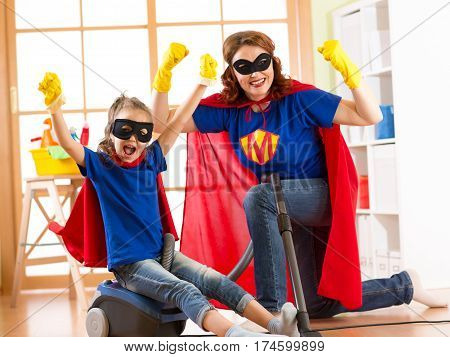 Strong superhero housewife and her kid daughter ready to room cleaning. Housework and household concept.