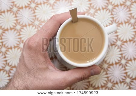 Hand holding cup of instant coffee with milk