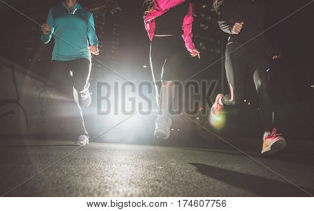 Three women running in the night in the city center