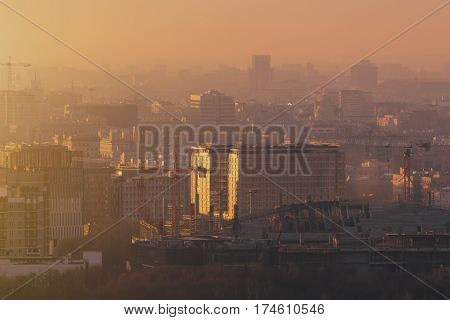Close-up shooting from top of morning metropolitan city: huge stadium under construction with cranes and beams residential buildings and districts multiple facades hazy horizon Moscow Russia