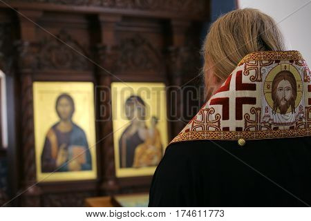 Orthodox bishop praying in front of altar icons in the church