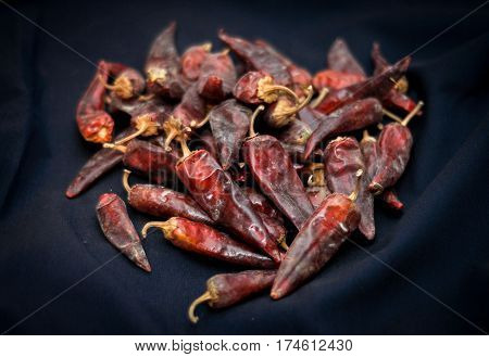Dried red peppers are lying in a heap glitering with different shades of red