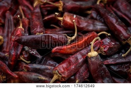 Dried red peppers are lying in a heap glitering with different shades of red