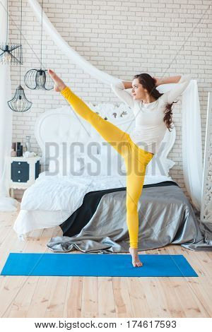 Woman dances in the morning in the bedroom near the bed.