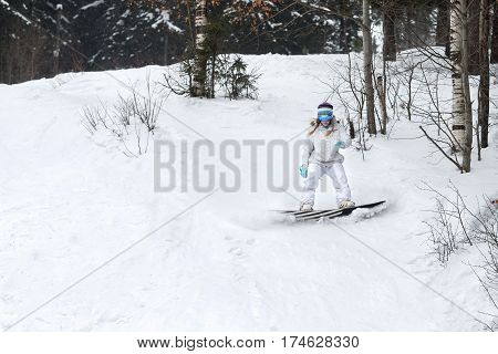 Young woman snowboarder in motion on snowboard in mountains.
