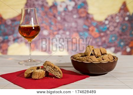 Italian cantucci biscuits over a red napkin and a glass of vin santo wine on background