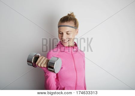 Portrait of fitness young woman wearing pink sports wear. Fresh healthy stylish sport girl posing close to white wall.