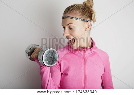 Portrait of fitness young woman wearing pink sports wear. Fresh healthy stylish sport girl posing close to white wall.