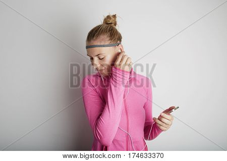 Portrait of fitness young woman wearing pink sports wear. Fresh healthy stylish sport girl listening energetic music.