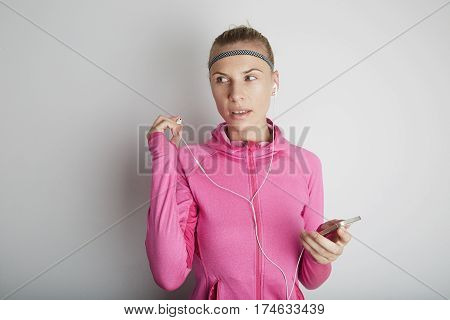 Portrait of fitness young woman wearing pink sports wear. Fresh healthy stylish sport girl listening energetic music.