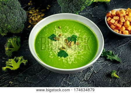 Dietary Broccoli smooth cream soup with sprinkle of sunflower seeds, parsley leaves and croutons on stone table
