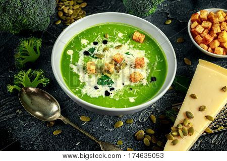 Dietary Broccoli smooth cream soup with sprinkle of sunflower seeds, parsley leaves and croutons on stone table