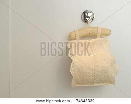 Roll tissue cloth lace fabric cover with toilet paper roll for sanitary inside hanging on white background bathroom closed up with space