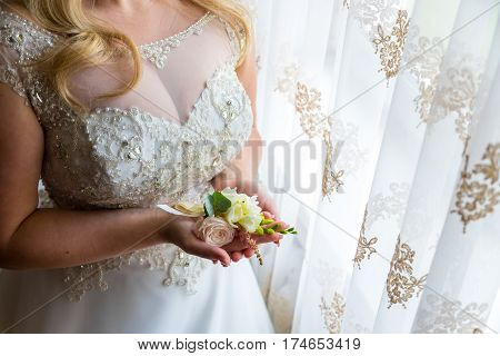 Bride holding a buttonhole. Gentle hand of the bride holding boutonniere for the groom.