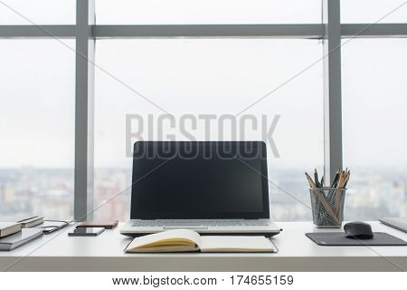 Workplace with notebook laptop Comfortable work table in office with windows and city view