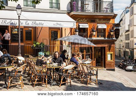 Paris France - July 06 2016: A traditional restaurant in Paris in the Butte Montmartre. Parisians and tourists enjoy food and drinks under the sun. Montmartre area is most popular destinations in Paris has lots of cozy cafes restaurants bistros night club