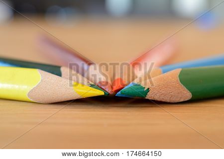Coloured pencils on wooden table closeup. Shallow depth of field.
