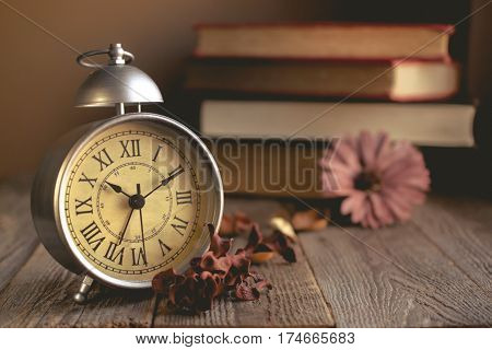 Roman Numeral in Vintage Alarm Clock and Stack of Book Background with Copy Space for Advertise or Web Promote about the Time or Nostalgia Concept