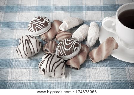Cup of tea and delicious cookies on blue checkered tablecloth