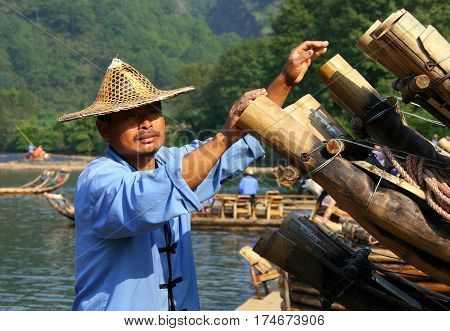 WUYISHAN, FUJIAN, CHINA - OCT 20, 2009: Chinese man preparing bamboo rafts to travel on the River of Nine Bends. Bamboo rafting is very popular tourist attraction in the scenic area of Wuyi mountains