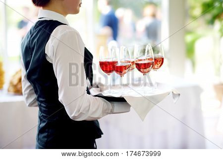 Waitress Holding A Dish Of Champagne And Wine Glasses At Festive Event