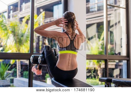 portrait of an athletic woman doing exercising abdominals work-out lying in gym at luxury hotel at summer.