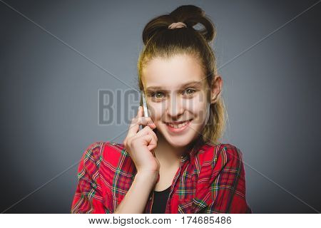 Closeup Portrait of happy girl with mobile or cell phone on gray background.