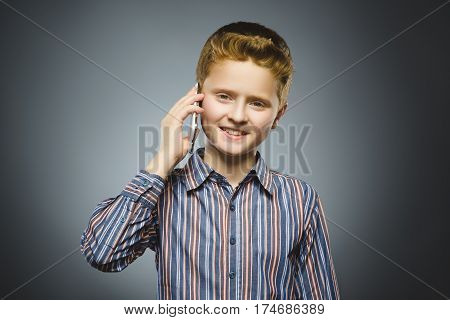 Closeup Portrait of happy boy with mobile or cell phone on gray background.