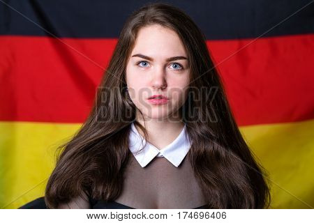 Portrait of a beautiful calm brunette girl in the background of the German flag