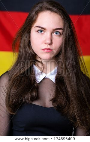 Portrait of a beautiful calm brunette girl in the background of the German flag