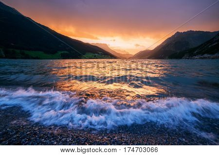 Beautiful view of the lake Resia. Dramatic sky and colorful sunset. Alps, Italy, Europe.