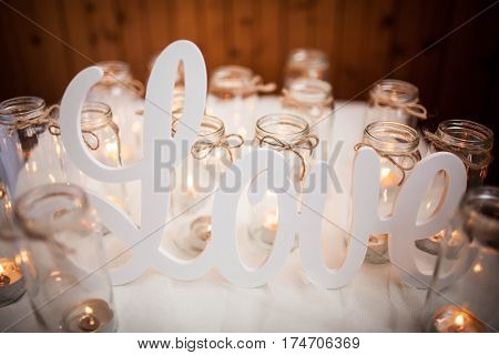 The word LOVE on white cloth around burning candles. Handmade.