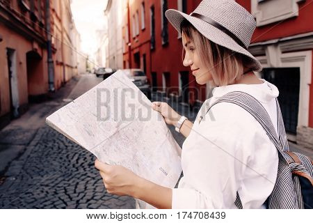 Travel guide. Young female traveler with backpack and with map on the street. Travel concept. Adventure