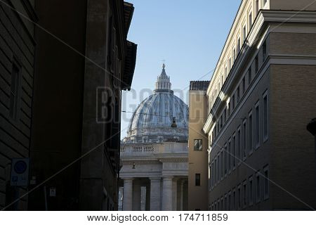 Saint Peter's dome in Rome seen through a typical roman alley
