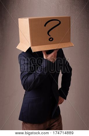 Young man standing and gesturing with a cardboard box on his head with question mark