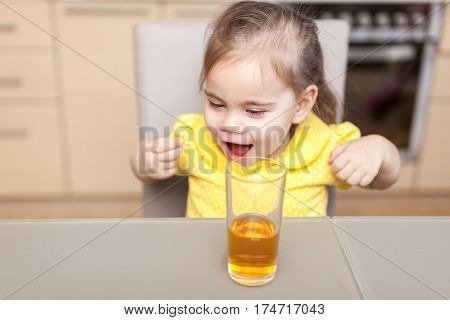 little girl drinking apple juice at the kitchen