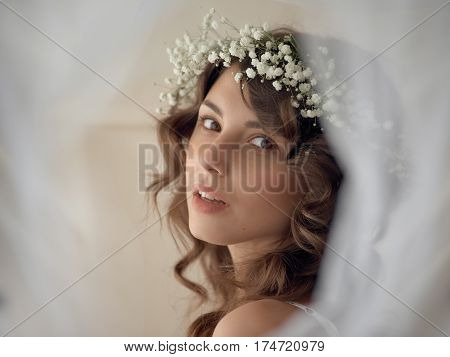 Portrait of sensual woman in circlet of flowers looking at camera