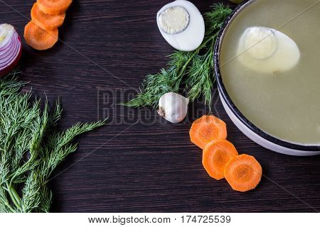 Soup with sorrel vegetables and boiled egg red onion carrots garlic dill on dark wooden table
