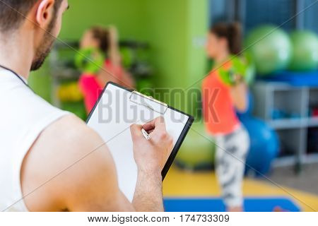 Two girl exercising at the gym with a personal trainer