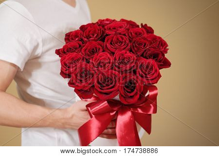 Man In White T Shirt Holding In Hand Rich Gift Bouquet Of 21 Red Roses. Composition Of Flowers In A