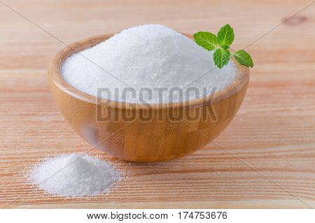 birch sugar xylitol in a wood bowl with mint on wooden background