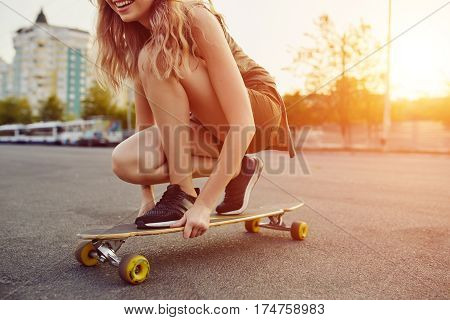 Beautiful young girl with tattoos riding on his longboard on the road in the city in sunny weather. Extreme sports. Close up