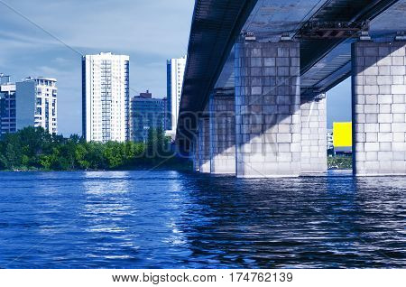 the bridge through the river against the background of a city landscape with high houses