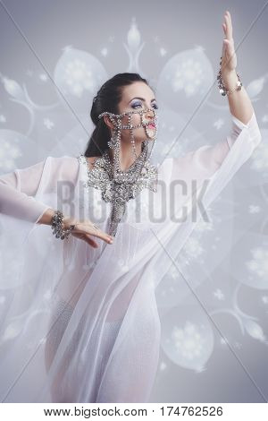 Sexy oriental belly dancer dancing in silk weil outfit glowing arabic ornamental background