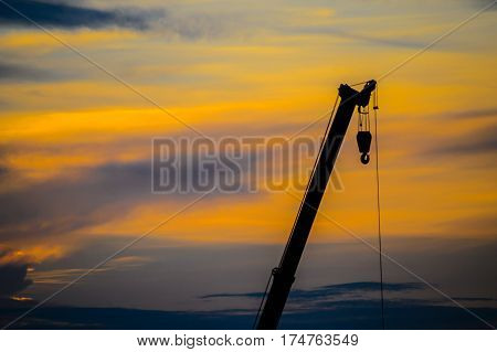mobile crane arm operating silhouettes at sunset