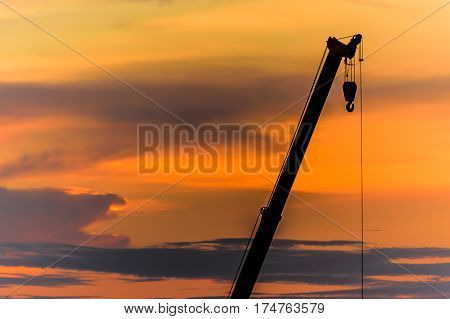 mobile crane arm operating silhouettes at sunset