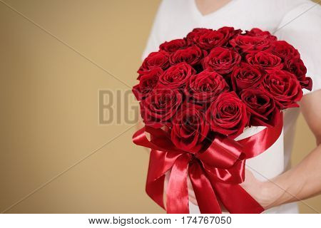 Man In White T Shirt Holding In Hand Rich Gift Bouquet Of 21 Red Roses. Composition Of Flowers In A