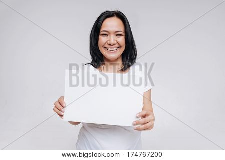 Smile is your best response. Unique wonderful bright lady holding up a white sign while wearing casual clothes accentuating her natural beauty