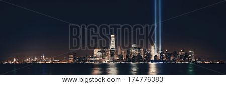 New York City downtown skyline at night panorama over Hudson River and September 11 tribute light